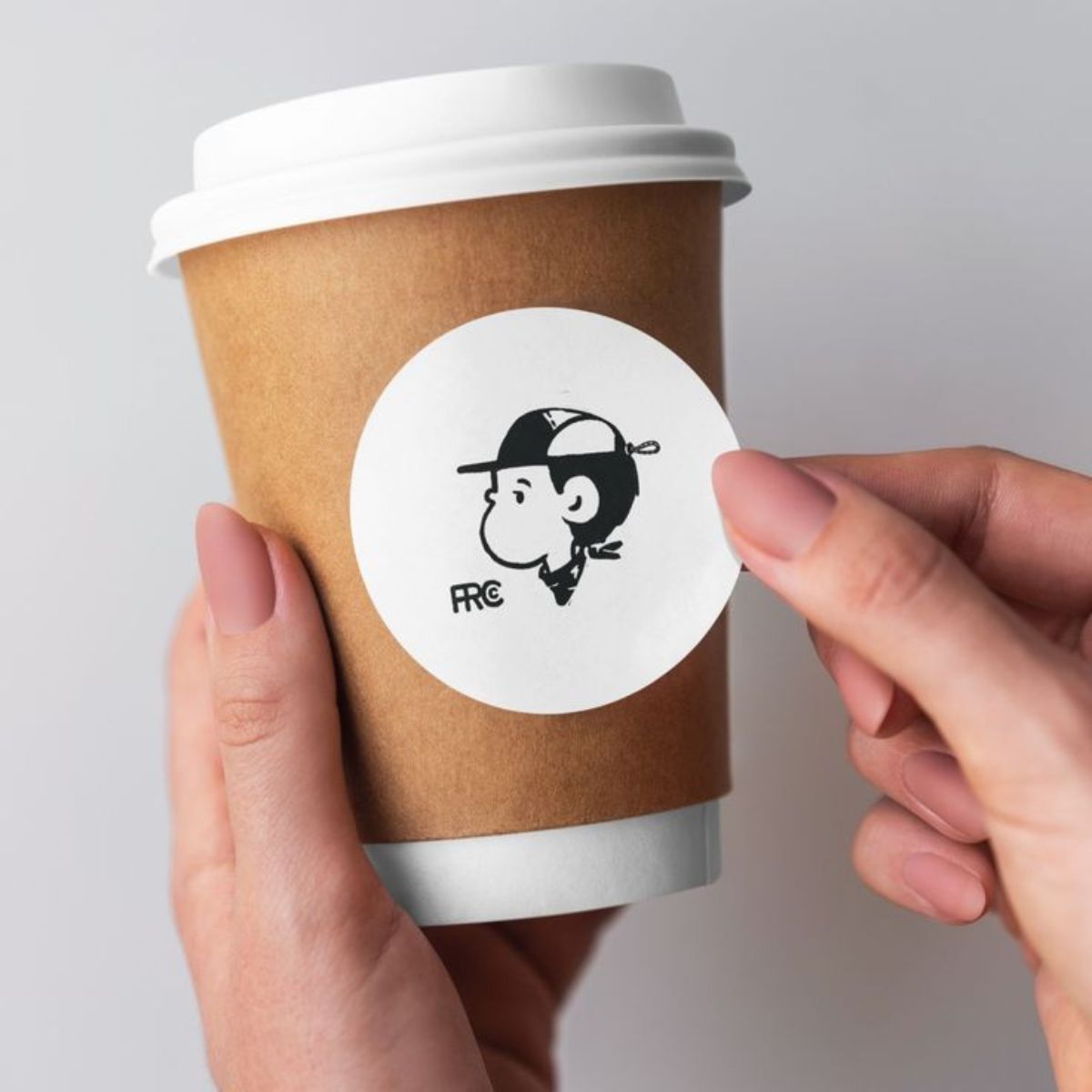 round paper sticker being pasted on a coffee cup